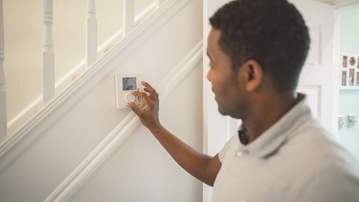 Person adjusting thermostat at home