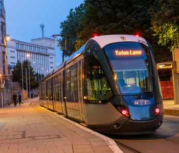 Tram in Nottingham city centre with Nottingham Trent University building in background